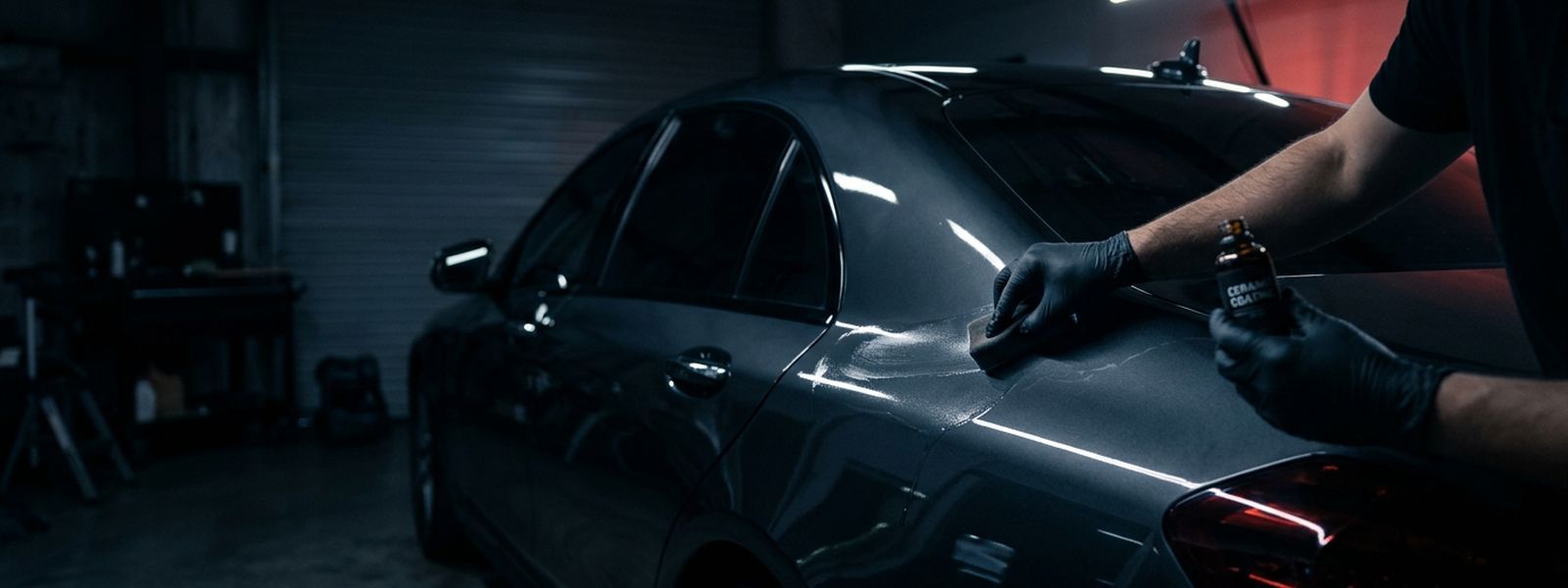 Ceramic coating being applied to a dark panel under detail lighting
