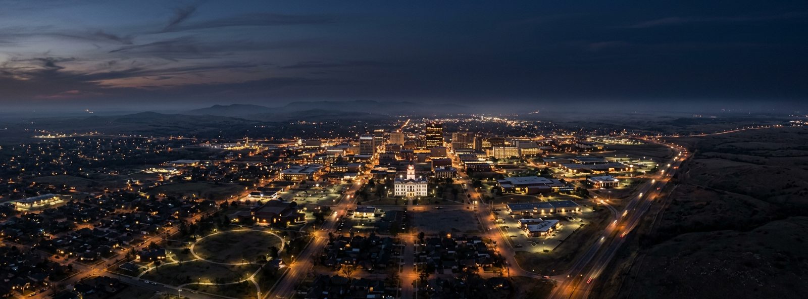 Aerial view of the Lawton, Oklahoma skyline at dusk, illustrating the metro area TactStack serves structural steel businesses in